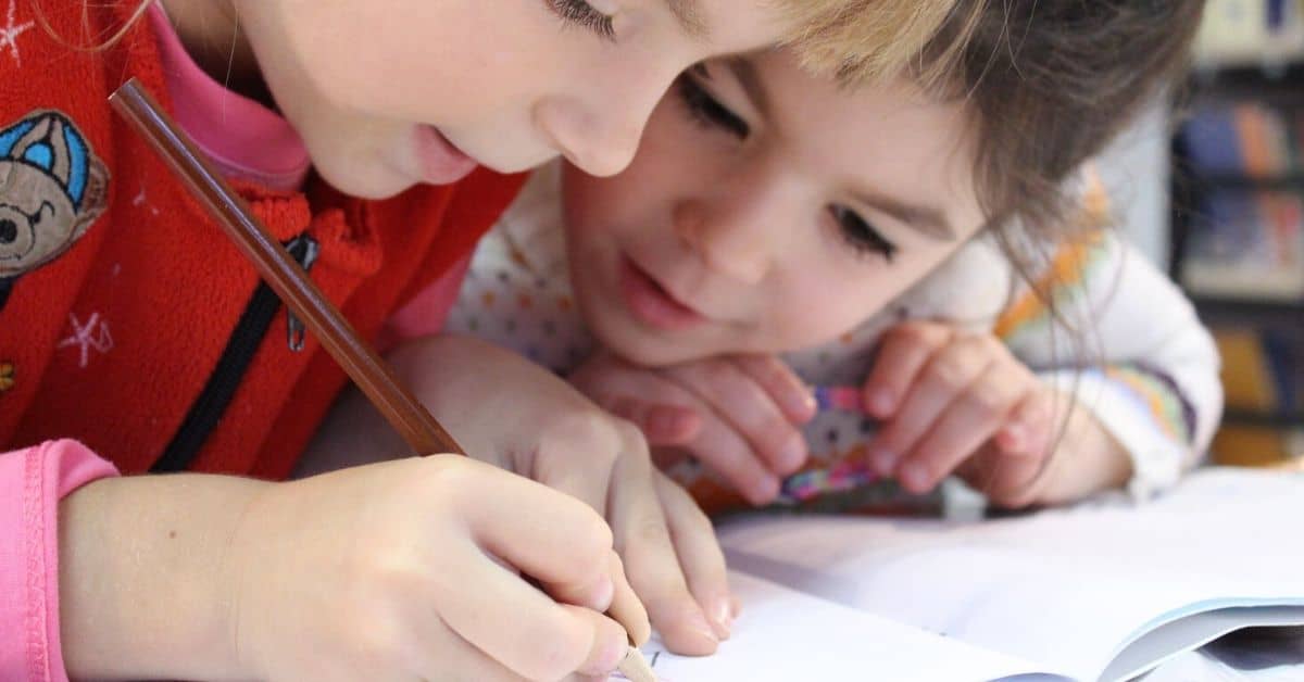 Two sisters write in a notebook