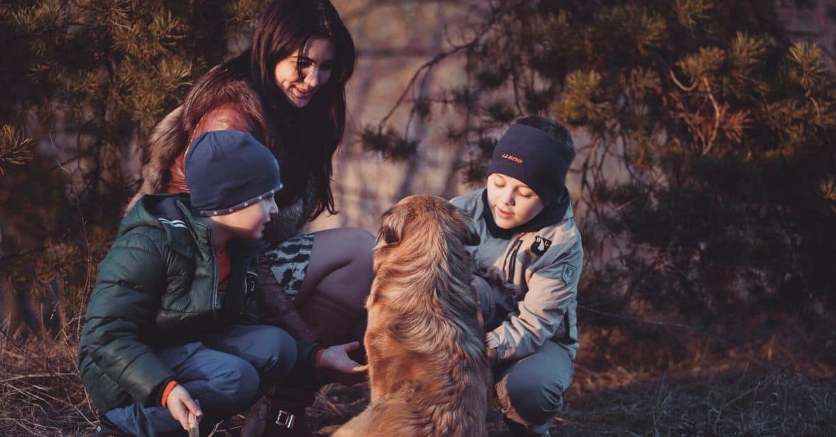 Mom and sons sit with dog outside