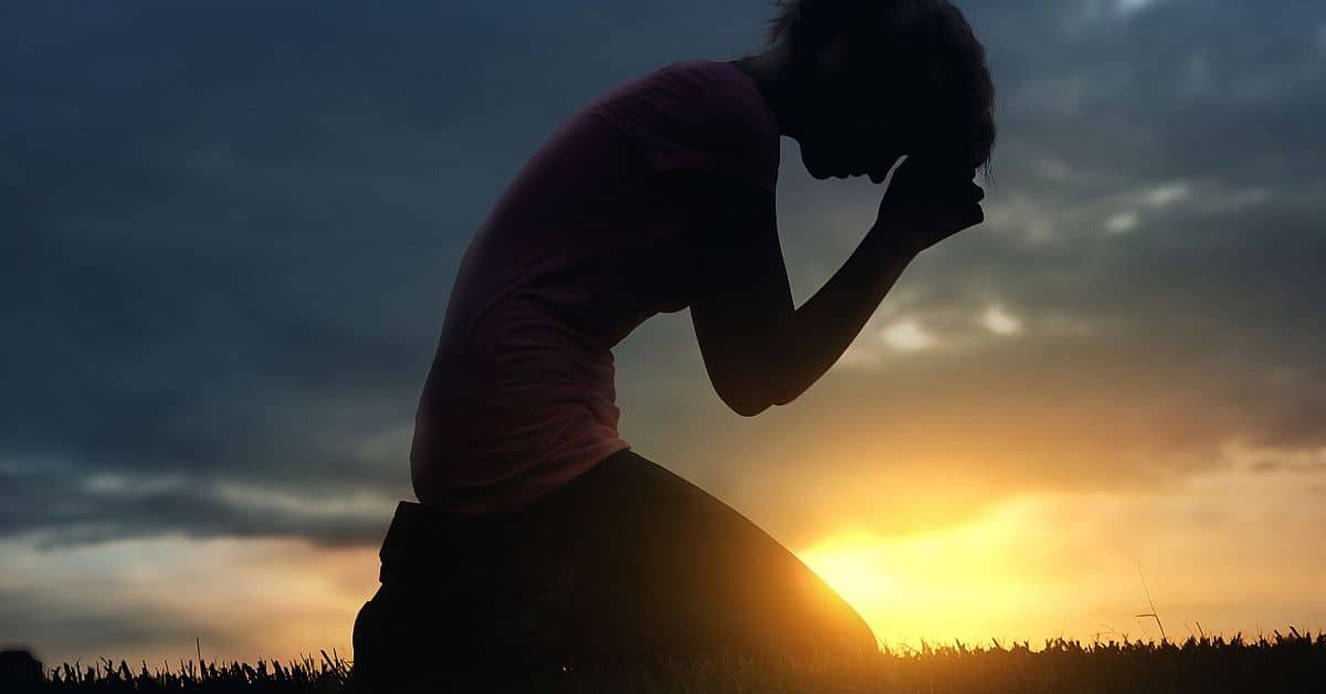 Woman kneels to pray