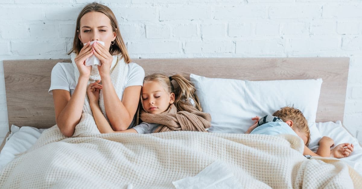 Sick mom lies in bed with sick children